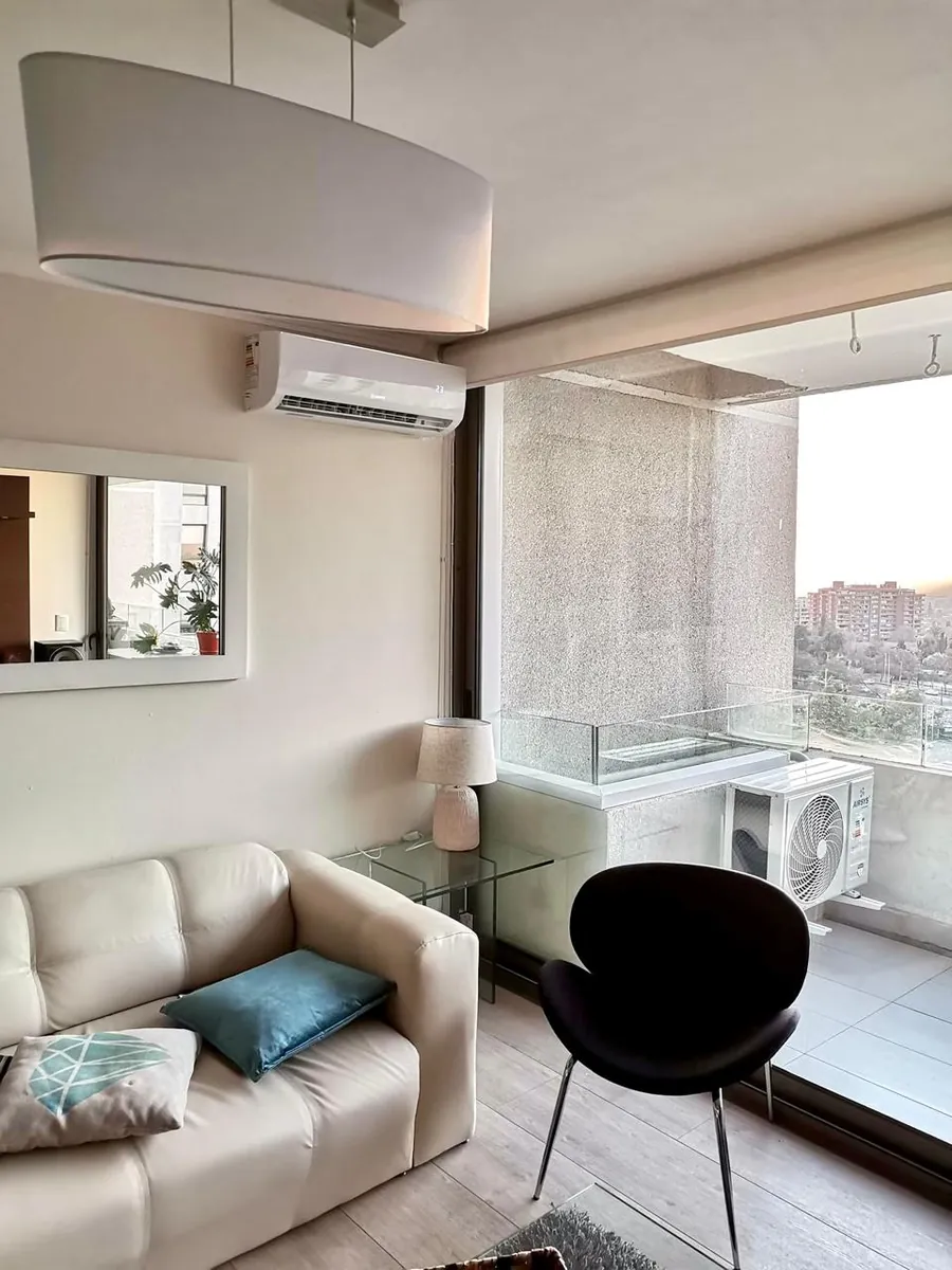 Living con aire acondicionado split instalado sobre la ventana y la unidad exterior en el piso de la terraza